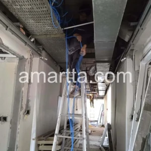 teknisi melakukan penarikan kabel lan di plafon