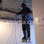 teknisi melakukan instalasi kabel lan di plafon pabrik