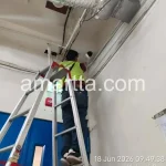 teknisi dengan bantuan tangga memasang Kabel CCTV